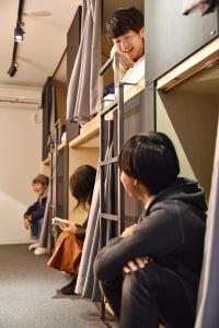 un groupe de personnes assises dans une rangée de lits superposés dans l'établissement Tomarigi Hostel Cafe Bar, à Kōchi