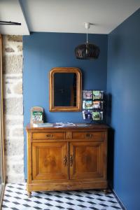 a wooden dresser with a mirror on a blue wall at Les Gîtes de l’Oree in Bécherel