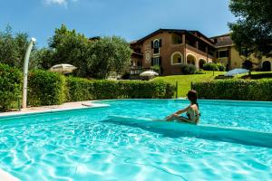 a woman sitting in a swimming pool in front of a house at Villa Santa Caterina in Manerba del Garda