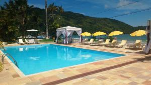 a swimming pool with chairs and umbrellas next to the water at Hotel Torremolinos in Ubatuba