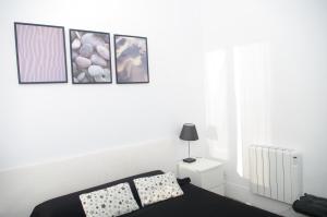 a white bedroom with a bed and three pictures on the wall at Carlos & Ana Amplio Apartamento 4 Habitaciones Centro Valencia in Valencia