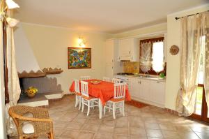 une cuisine avec une table et des chaises dans une pièce dans l'établissement villa i ginepri, à Budoni