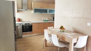 een keuken met een houten tafel en witte stoelen bij Casa da Aldeia Velha - Country House in Aldeia Velha