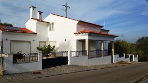 een wit huis met een hek aan de kant van een weg bij Casa da Aldeia Velha - Country House in Aldeia Velha