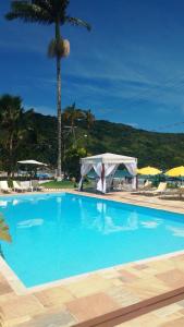 a large blue swimming pool with a tent and palm trees at Hotel Torremolinos in Ubatuba