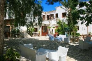 un patio con sedie e tavoli bianchi e un edificio di Casa Vacanze Il Cortile a Custonaci