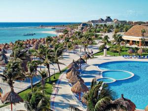 a resort with a swimming pool and palm trees and the ocean at Bahia Principe, TAO, Luxury Penthouse in Akumal