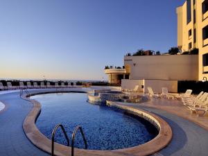 une piscine avec des chaises et un bâtiment dans l'établissement Park Hotel Mirabeau, à Montepaone