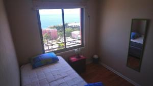 een slaapkamer met een raam met een bed en een spiegel bij Edificio Los Navegantes, Valparaiso in Valparaíso +35 foto's