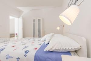 a white bedroom with a bed and a lamp at Apartment Maja in Novalja in Novalja