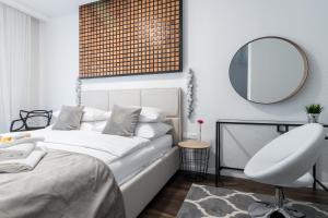 ein Schlafzimmer mit einem Bett, einem Spiegel und einem Stuhl in der Unterkunft GA Luxury Apartments W19 in Krakau