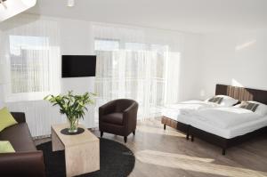 ein Schlafzimmer mit einem Bett, einem Stuhl und einem Sofa in der Unterkunft ADAPT APARTMENTS BERLIN - Adlershof in Berlin