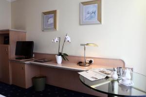 Habitación de hotel con escritorio, TV y mesa. en Hotel Ambiente Garni, en Múnich