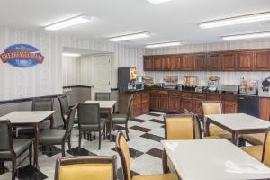 a restaurant with tables and chairs and a kitchen at Baymont by Wyndham Cleveland in Cleveland