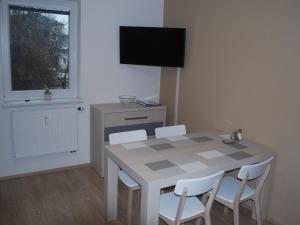 a dining room table with white chairs and a television at Apartmán U Zámku in Loučná nad Desnou