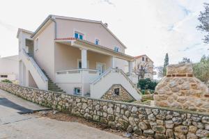 a large white house with a stone wall at Apartment Maja in Novalja in Novalja
