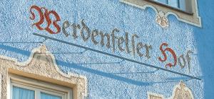 un cartello sul lato di un edificio blu di Werdenfelser Hof a Garmisch-Partenkirchen