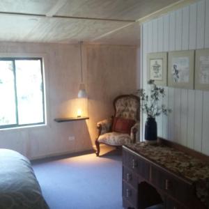 a bedroom with a bed and a chair and a window at Windswept Country Retreat in Ballandean