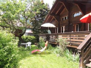 een huis met twee stoelen en een tafel en een paraplu bij Apartment Minnehaha- Chalet by Interhome in Lauenen