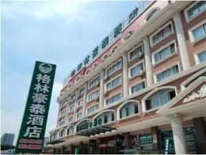 een groot gebouw met een bord ervoor bij GreenTree Inn Rizhao West Station Suning Plaza in Rizhao