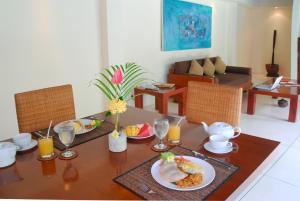 a dining room table with breakfast foods and orange juice at Nomad Hub Canggu Bali in Canggu