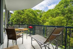 a balcony with chairs and a table with a view of trees at Perfect luxury for 2, Noosa Heads in Noosa Heads