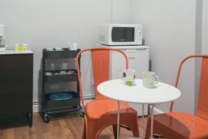 a kitchen with a white table and orange chairs and a microwave at Casual Serantes Bilbao in Bilbao
