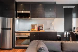 a kitchen with black cabinets and a couch in a room at Palo Alto Cottage by Stanford & Tech Companies in Palo Alto
