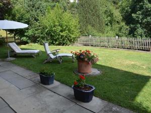 - une cour avec 2 chaises, un parasol et des fleurs dans l'établissement Apartment Sambi by Interhome, à Gstaad