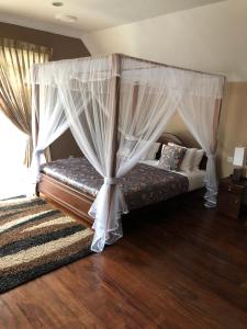 um quarto com uma cama de dossel e piso em madeira em Dorchester em Nuwara Eliya