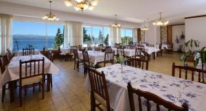 a dining room with white tables and chairs and windows at Hotel Concorde in San Carlos de Bariloche