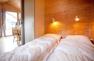 - 2 lits dans une chambre avec un mur en bois dans l'établissement Svalereden Camping Cottages, à Frederikshavn