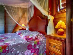 a bedroom with a canopy bed and a table with a lamp at Le Parc aux Orchidées in Pointe-Noire
