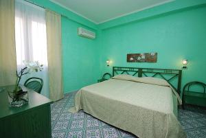 Dormitorio azul con cama y ventana en Hotel Il Melograno, en San Vito lo Capo