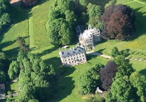 une vue aérienne sur une grande maison sur un champ verdoyant dans l'établissement Au Château, à La Lucerne-dʼOutremer
