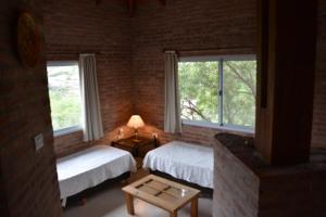a bedroom with two beds and two windows at Cabañas Del Rio in Mina Clavero