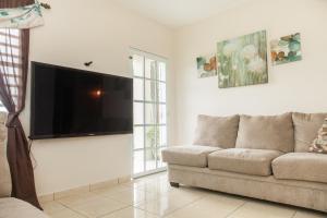uma sala de estar com um sofá e uma televisão de ecrã plano em Arenales Vacational House em Isabela