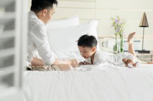 a man and a young boy laying on a bed at Four Seasons Hotel Singapore in Singapore
