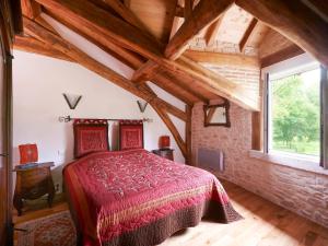 1 dormitorio con cama roja y pared de ladrillo en Holiday Home Moulin de Rabine by Interhome, en Cancon