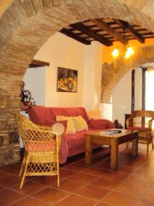 een woonkamer met een rode bank en een tafel bij Casa Rural El Zaguán in Jimena de la Frontera