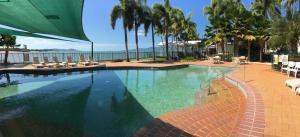 a large swimming pool with chairs and palm trees at Mariners North Holiday Apartments in Townsville