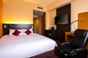 a hotel room with a bed and a chair at Chisun Grand Nagano in Nagano