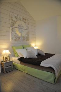 a bedroom with a large bed with green and white pillows at Hotel le P'tit Beaumont in Beaumont-en-Auge