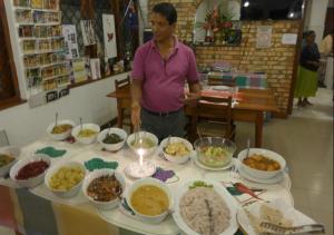 Een man die voor een tafel vol eten staat. bij Sharon Inn in Kandy