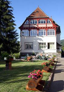 Una casa grande con gente sentada frente a ella. en Villa Du Sendenbach, en Muhlbach-sur-Munster