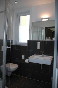 a bathroom with a sink and a toilet and a mirror at Von Korff´S Rest & Relax Hotel in Meschede