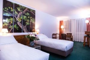 two beds in a hotel room with a painting on the wall at Hotel Sagitta in Geneva