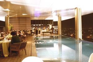北干巴鲁FOX Hotel Pekanbaru的一个带游泳池的餐厅,人们坐在桌子旁
