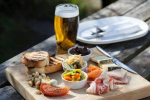 a wooden table with a plate of food and a glass of beer at The Wellington Hotel in Boscastle