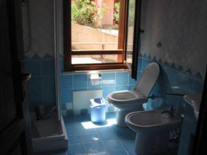 bagno con due servizi igienici, lavandino e finestra di Villetta fronte mare ad Arbus